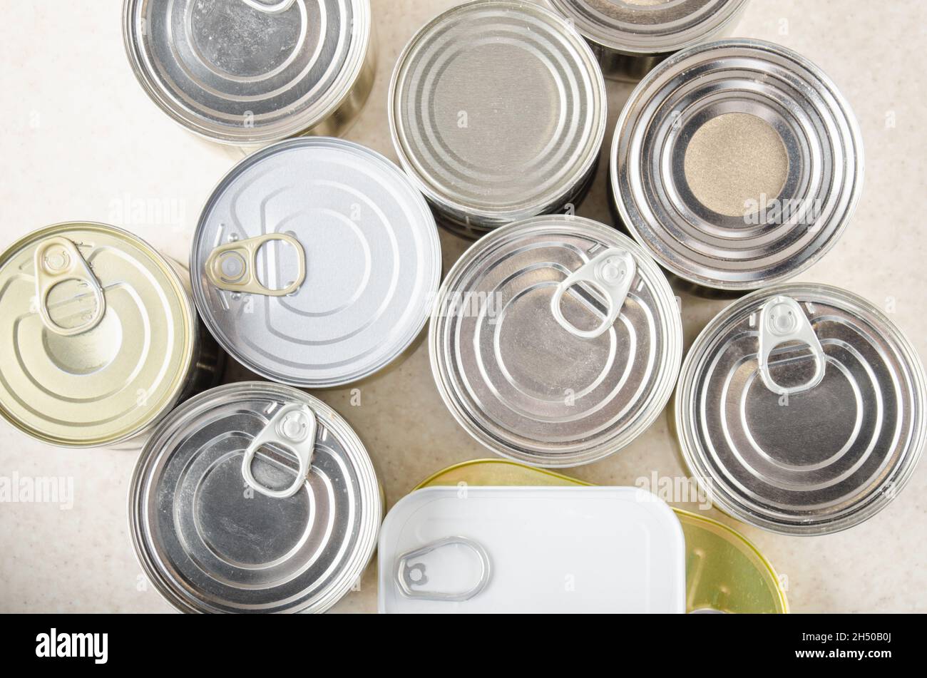 Flat lay view at various canned foods in tin cans on kitchen table, non-perishable, long shelf life food for survival in emergency conditions concept Stock Photo