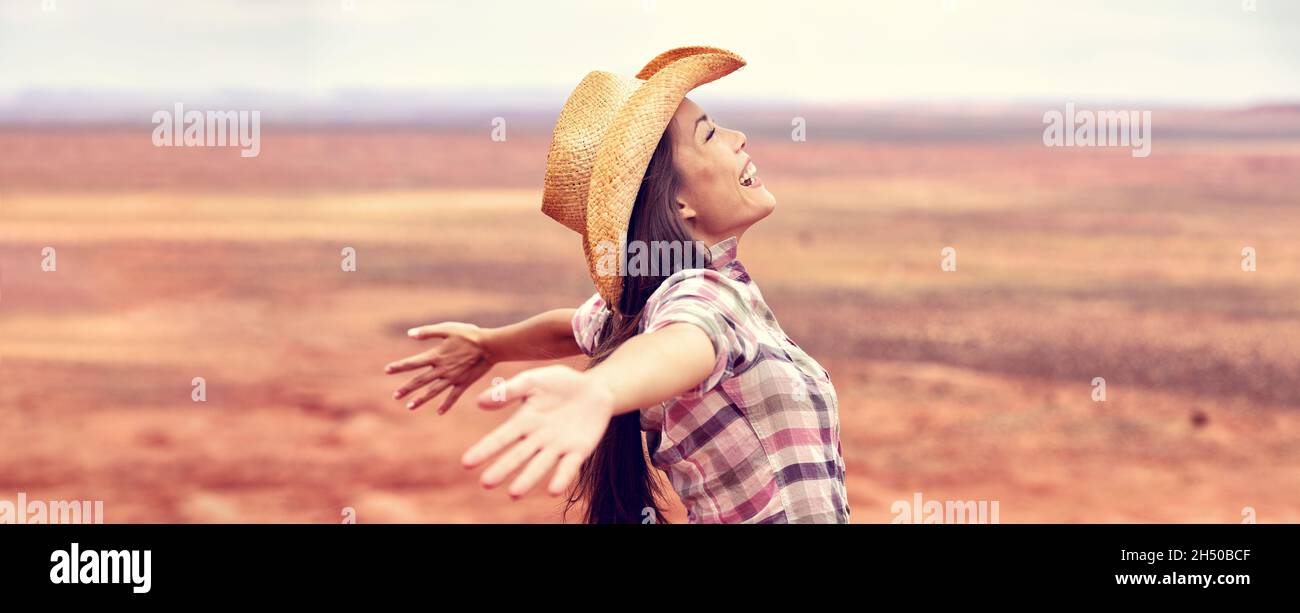 Cowgirl american woman happy with open arms in freedom wearing cowboy hat enjoying outback background panorama banner. Beautiful smiling multiracial Stock Photo