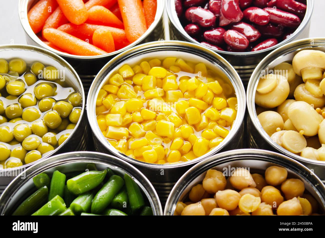 Canned vegetables in opened tin cans on kitchen table. Nonperishable