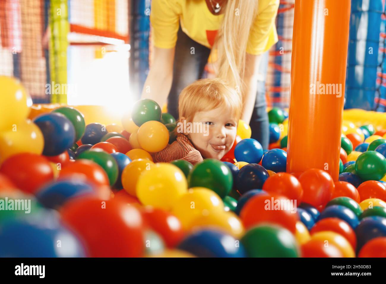 Happy Child Playing in Ball Pool. Kid Having Fun With Young Mother in