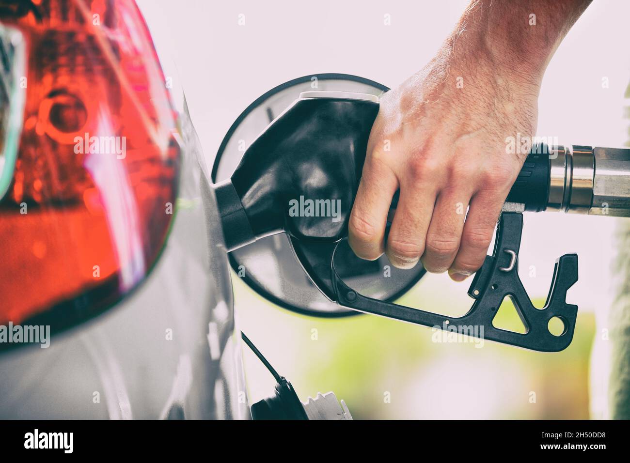 Gas pump person pumping fuel filling car tank at gas station. Man hand