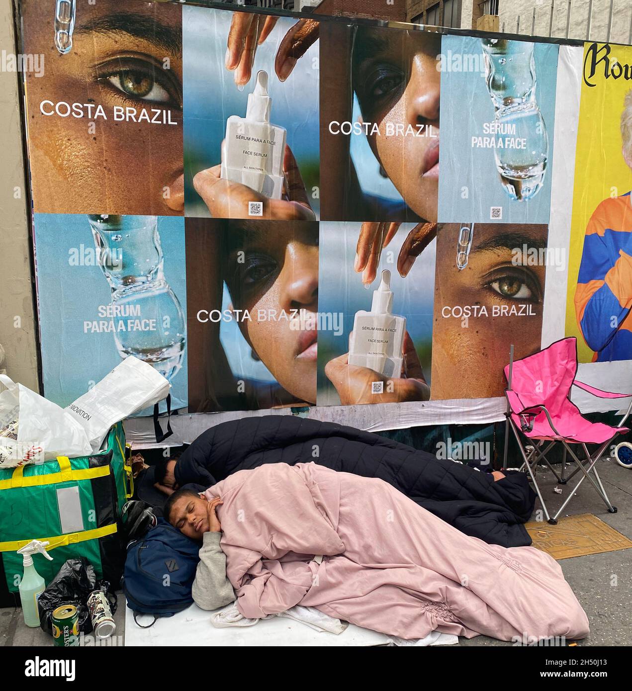 Two homeless people sleep along 6th Avenue in midtown Manhattan in the