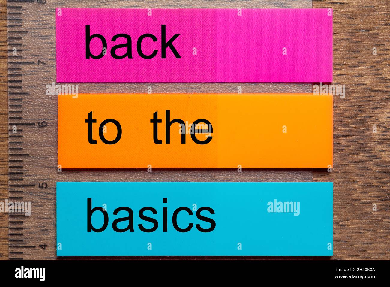 Three bookmark stickers with the phrase back to the basics on a dark natural wooden table Stock Photo