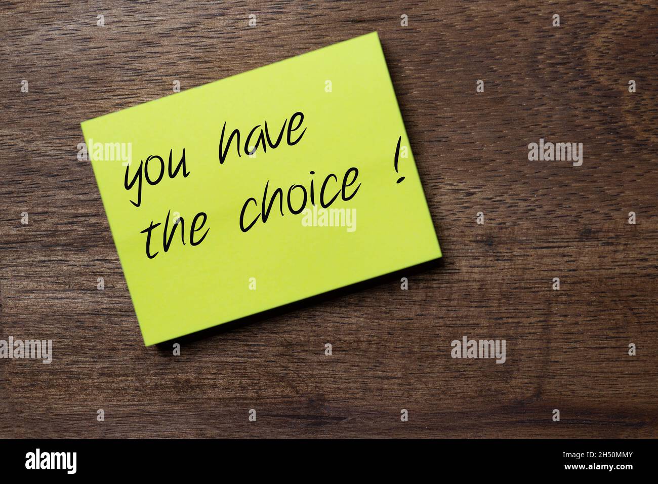 yellow sticker on a dark wooden background with the handwriting phrase to encourage a decision: you have the choice Stock Photo