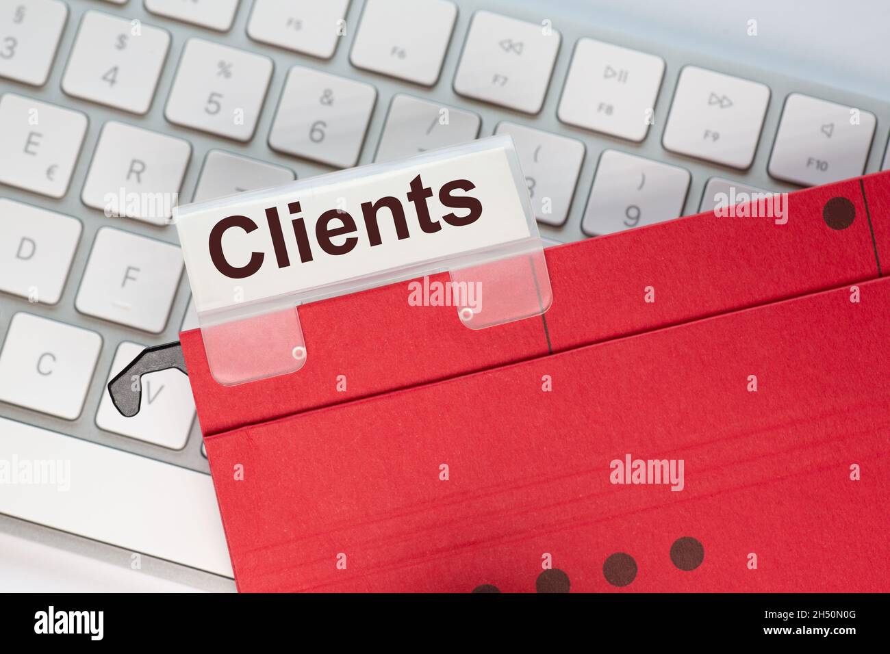 red hanging folder on a keyboard has a tab with the word clients on it Stock Photo