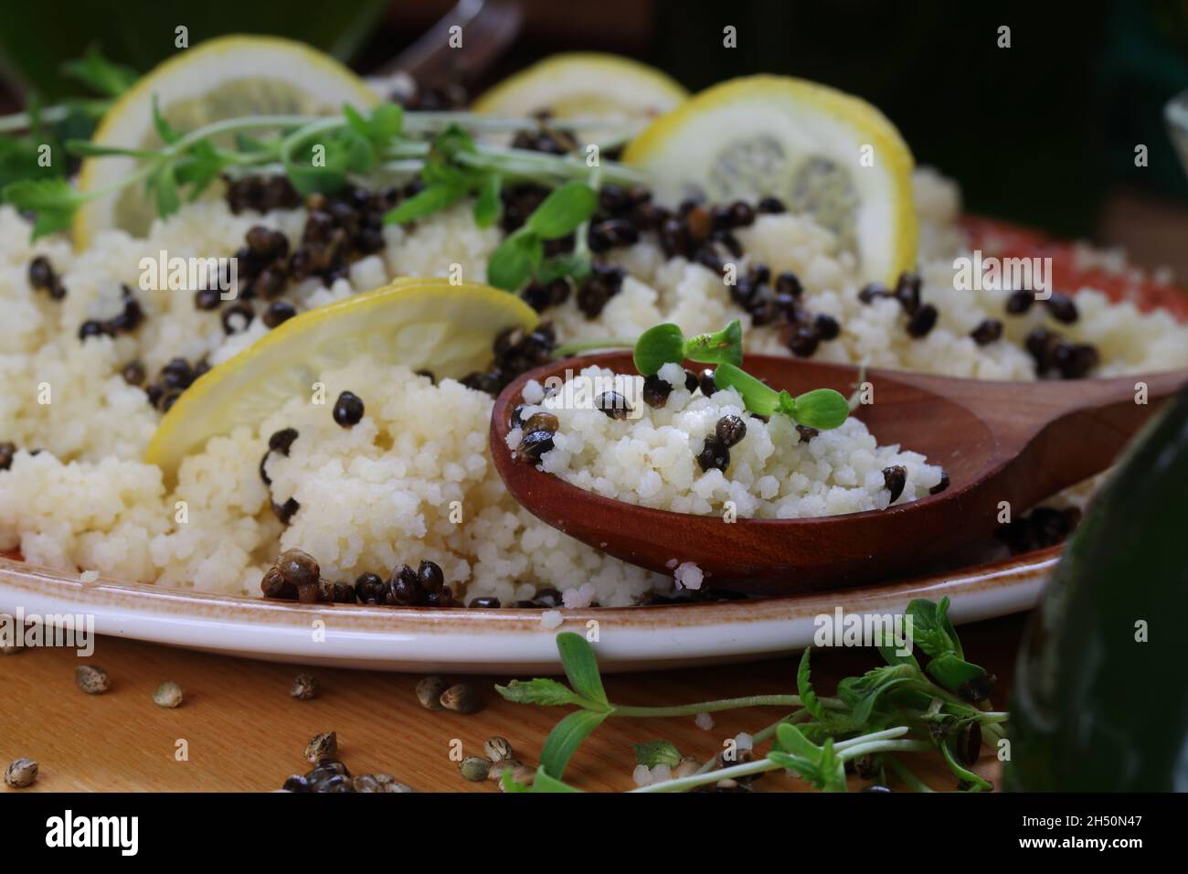 Couscous porridge with sprouts, sativa hemp seeds, lemon and wine Stock Photo