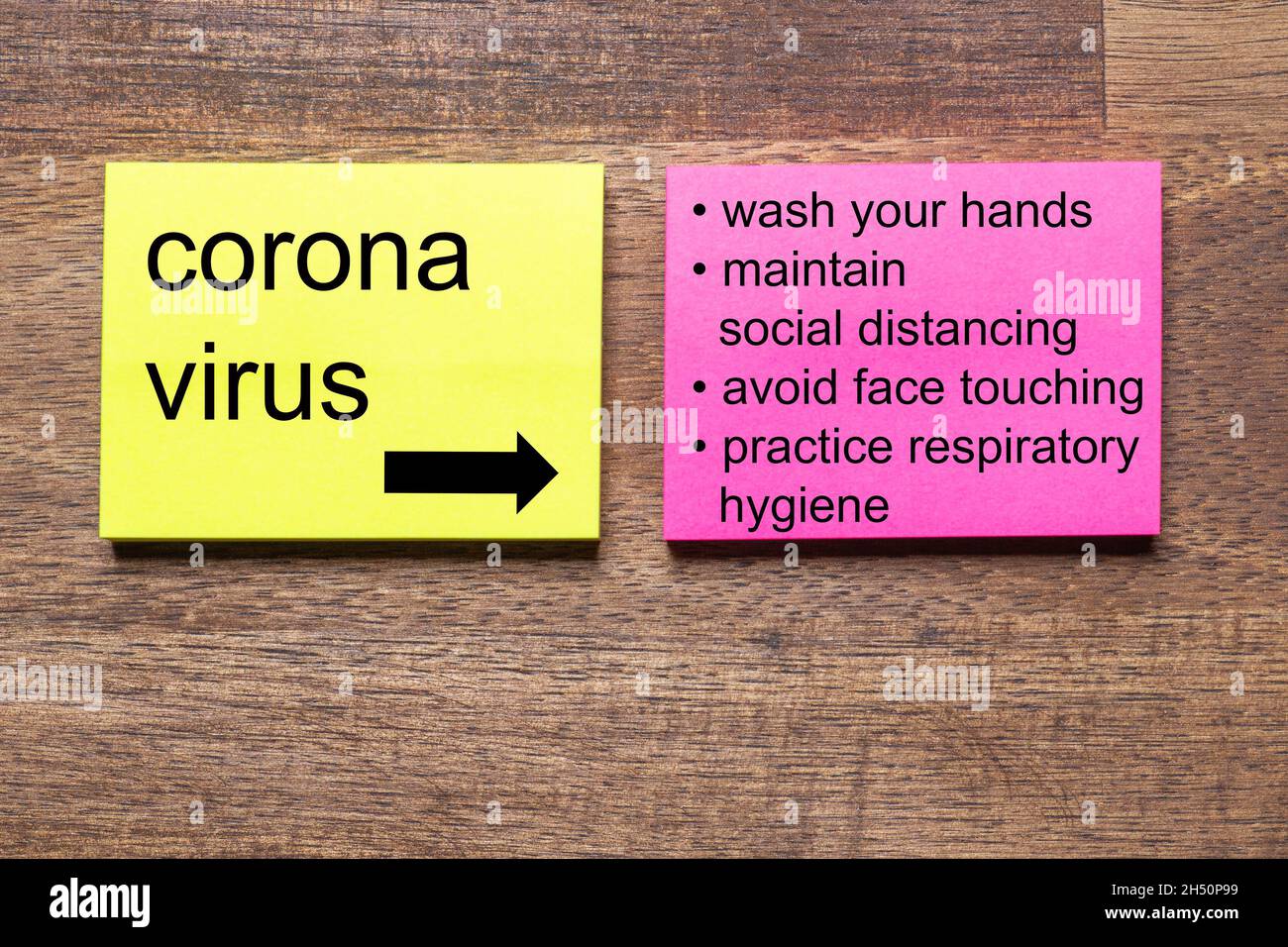 The words Corona virus with rules of conduct on yellow and red notes sticker on a dark wooden table Stock Photo