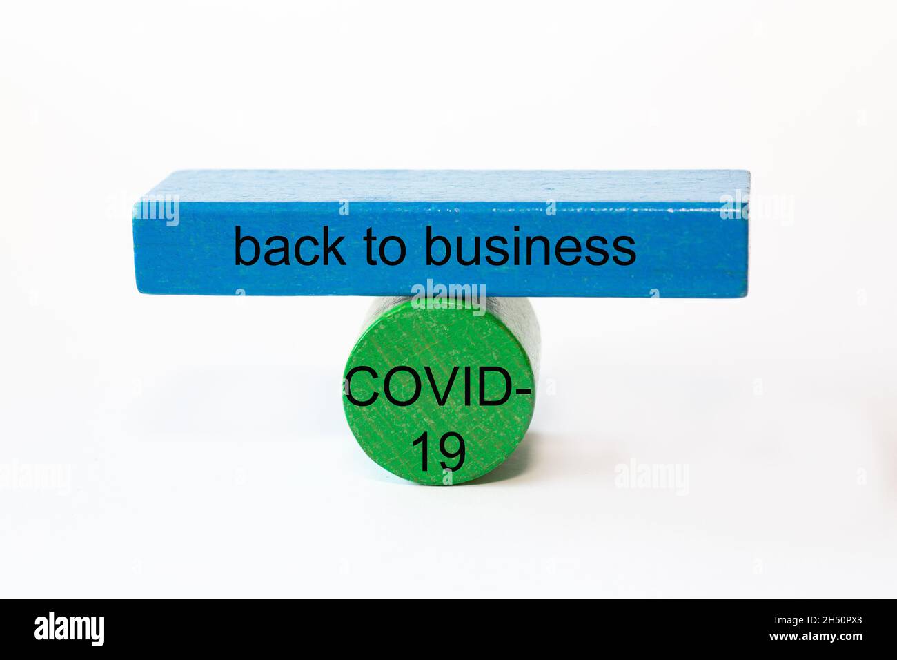colored fragments in fragile balance to underline the choice with the words: back to business COVID-19 Stock Photo