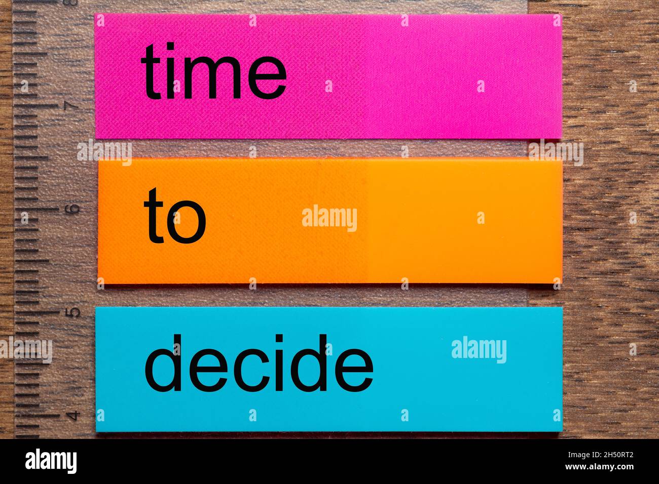 Three bookmark stickers with the words t ime to decide on a dark natural wooden table Stock Photo