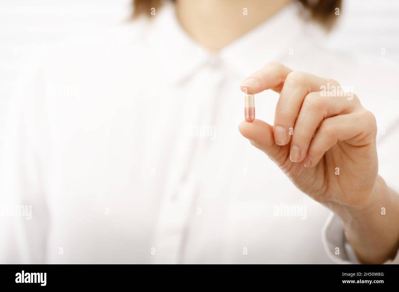 Caucasian female model holds pink pill in her hand closeup. Copy-space Stock Photo
