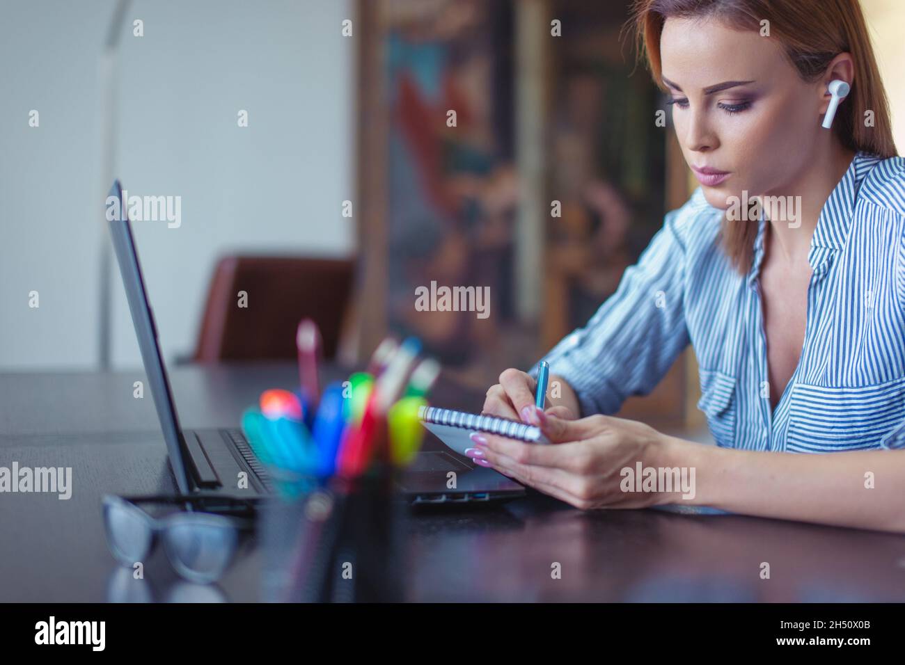 Young focused entrepreneur businesswoman making notes at laptop Stock Photo