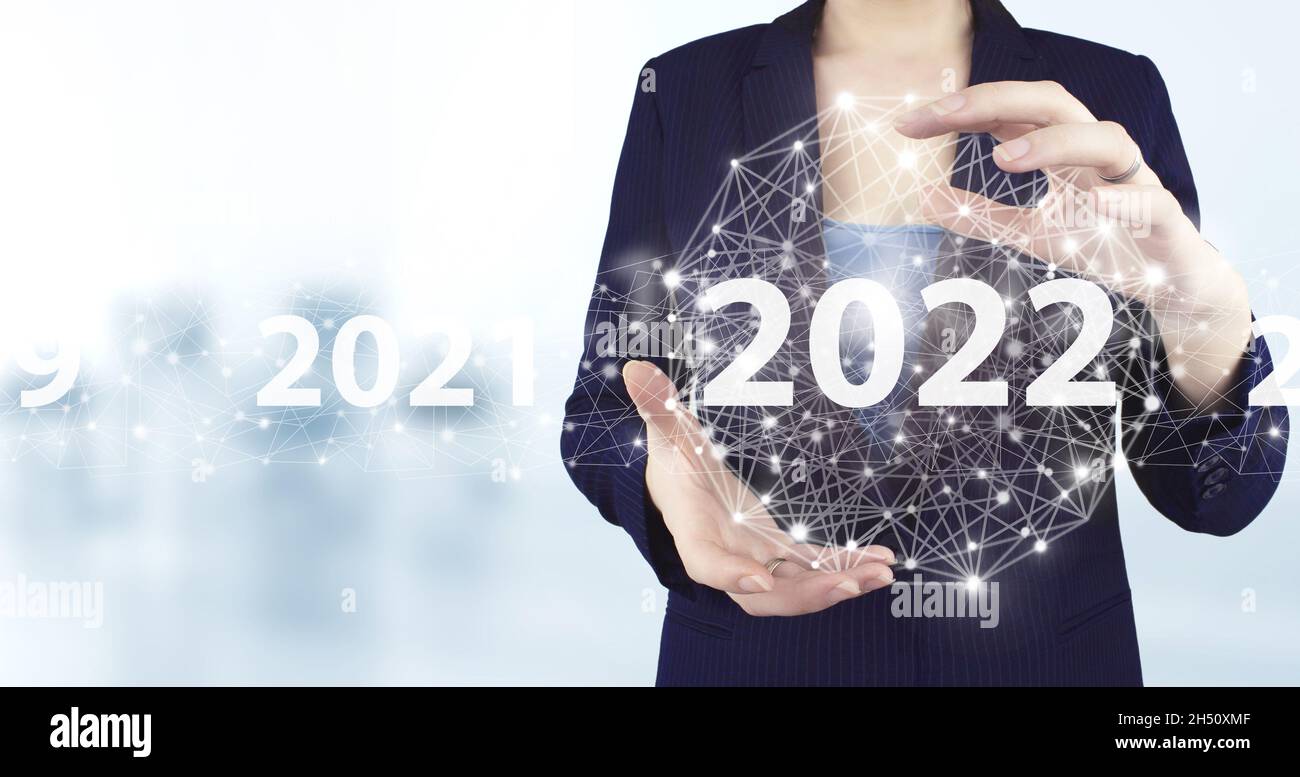 New year concept. Two hand holding virtual holographic 2022 icon with light blurred background. 2022 new year. Year two thousand and twenty two concep Stock Photo