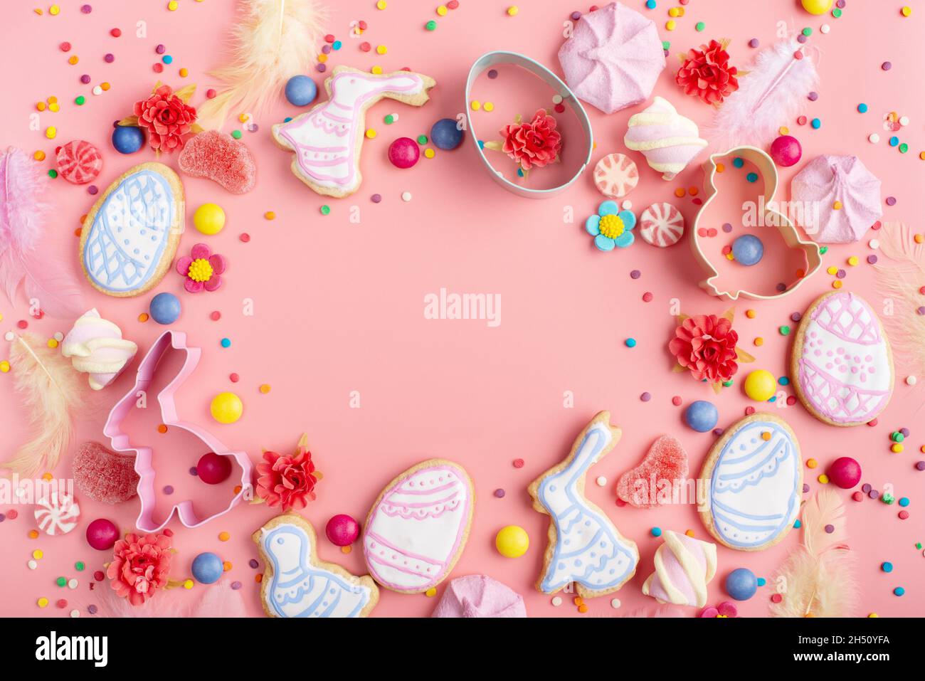 Sugar sprinkles, candies, Cookie cutters, Easter frosted cookies in shape of egg chicken and rabbit on pink background. Flat lay mockup with copy spac Stock Photo