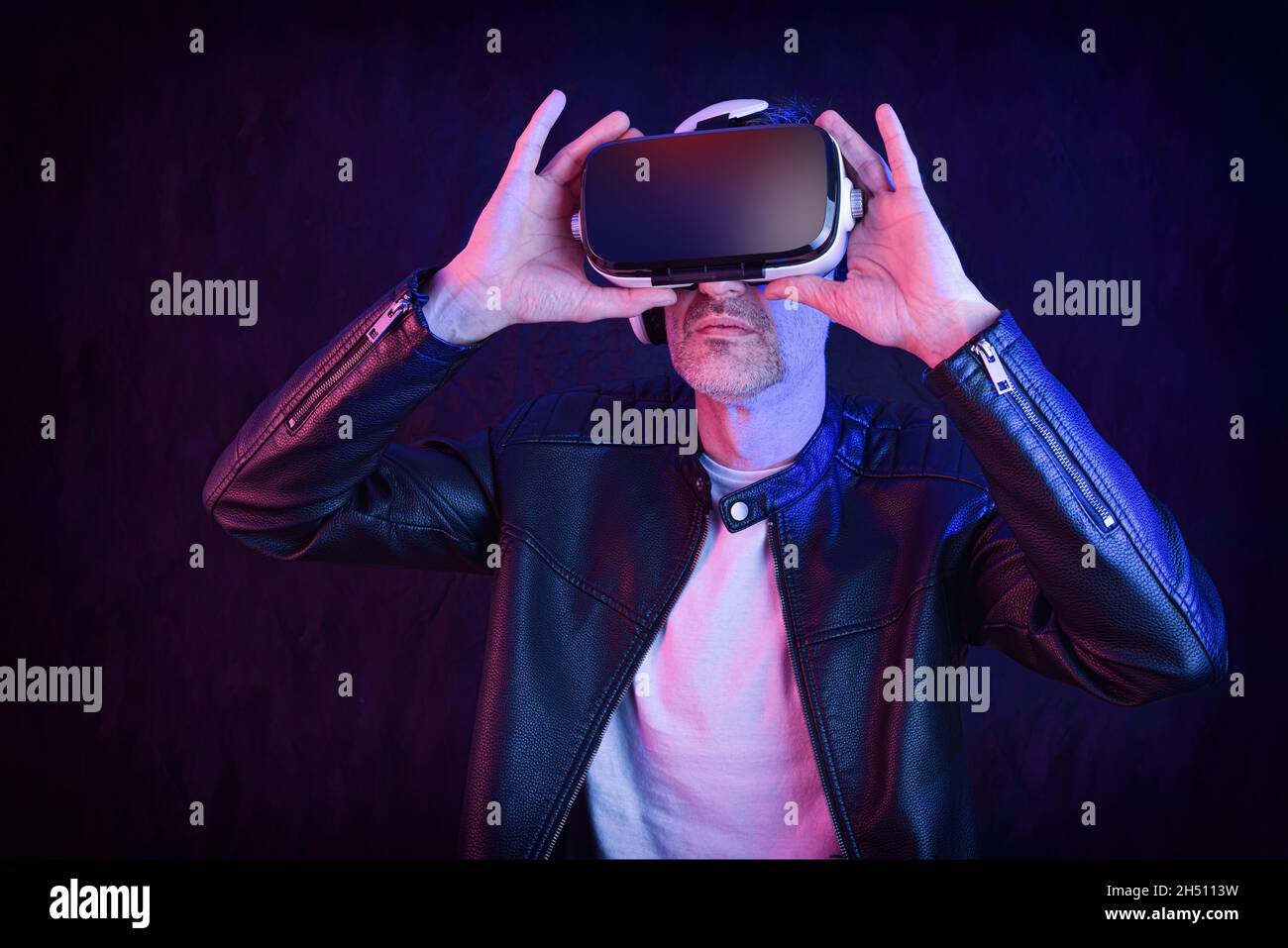 Smiling man dressed casual watching content in virtual reality glasses with dark isolated background Stock Photo
