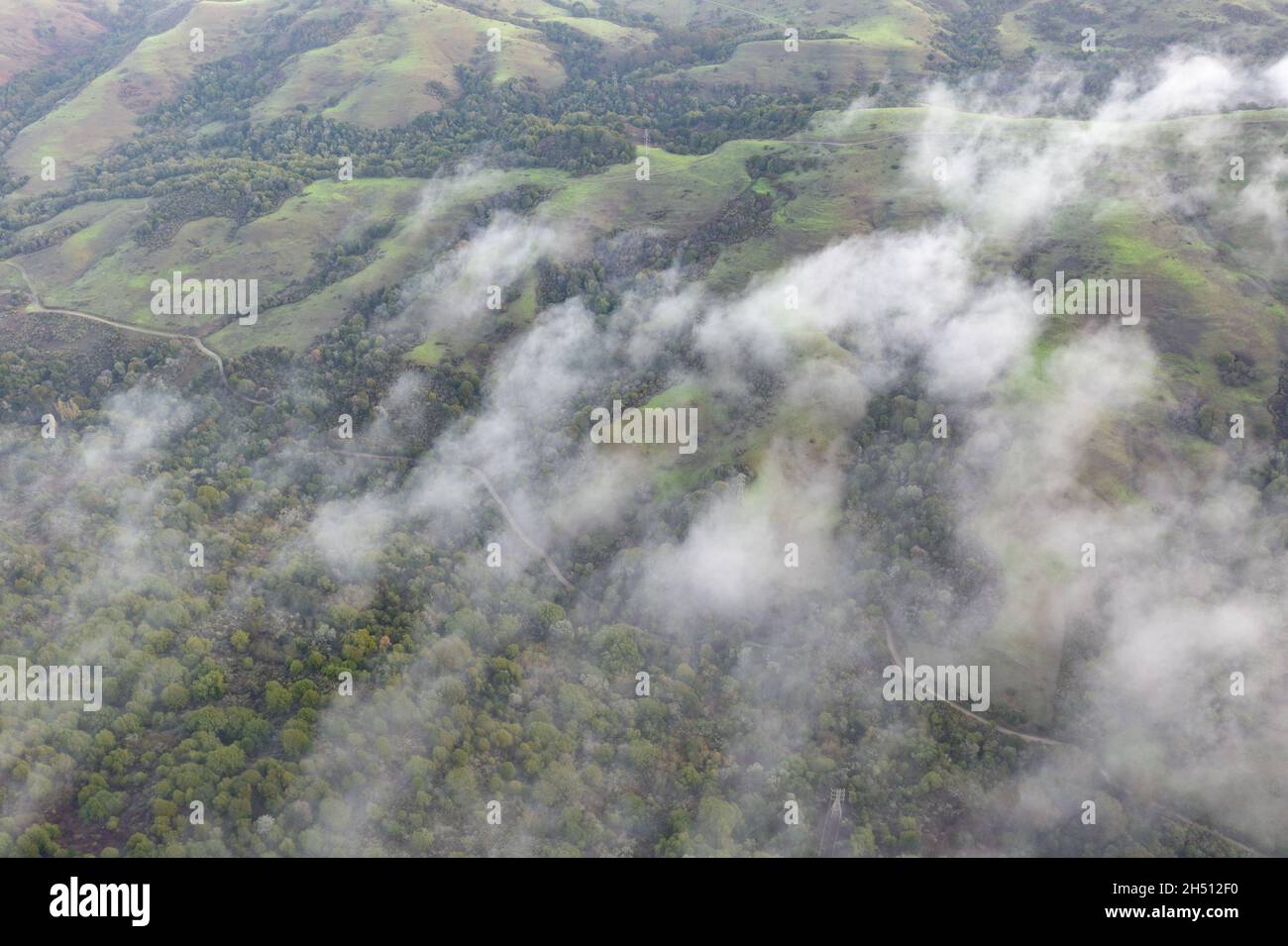 Low clouds drift across the rolling hills found east of San Francisco Bay, CA. This dry region turns green during the winter months due to rain. Stock Photo