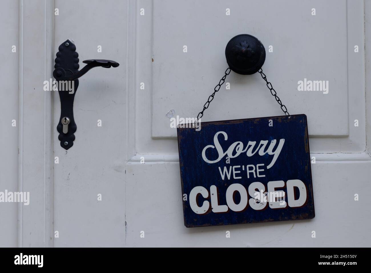 Sorry we are closed sign hanging on a white doors with door handle Stock Photo