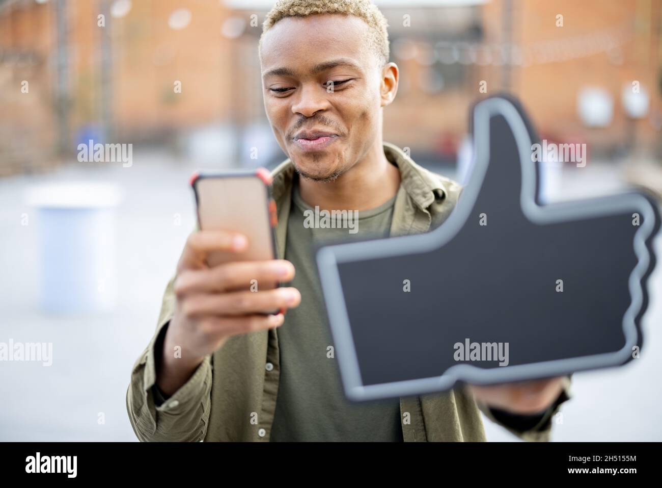 Guy use smartphone and showing thumb up Stock Photo