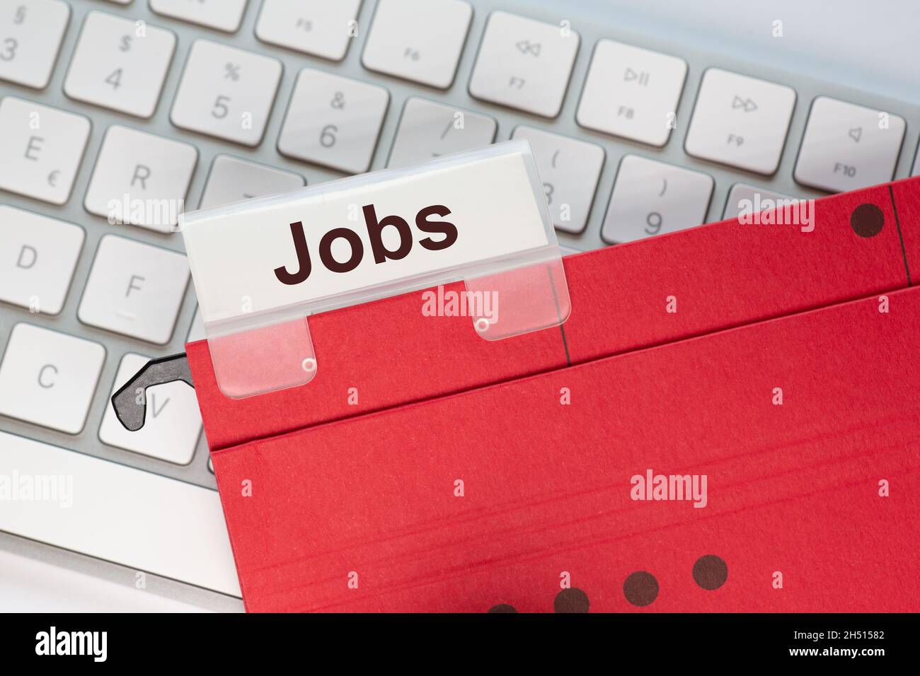 red hanging folder on a keyboard has a tab with the word Jobs on it Stock Photo