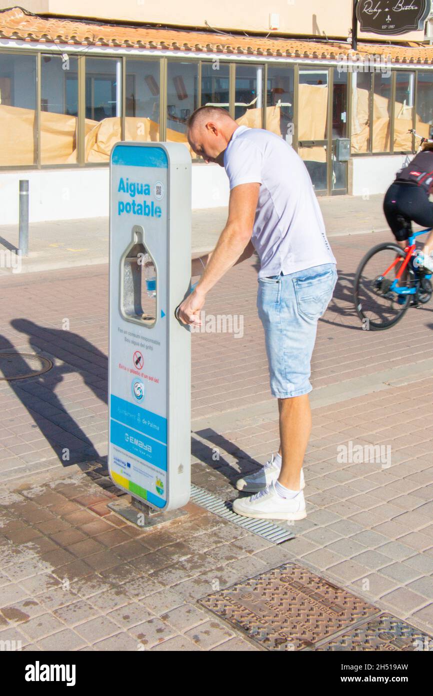 man refills container with drinkable water from dispenser on the promenade Can Pastilla Mallorca Spain Stock Photo