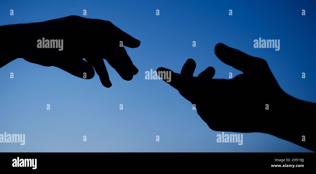 Hands support gesture silhouette. Giving helping hand. Care concept. Closeup Stock Photo