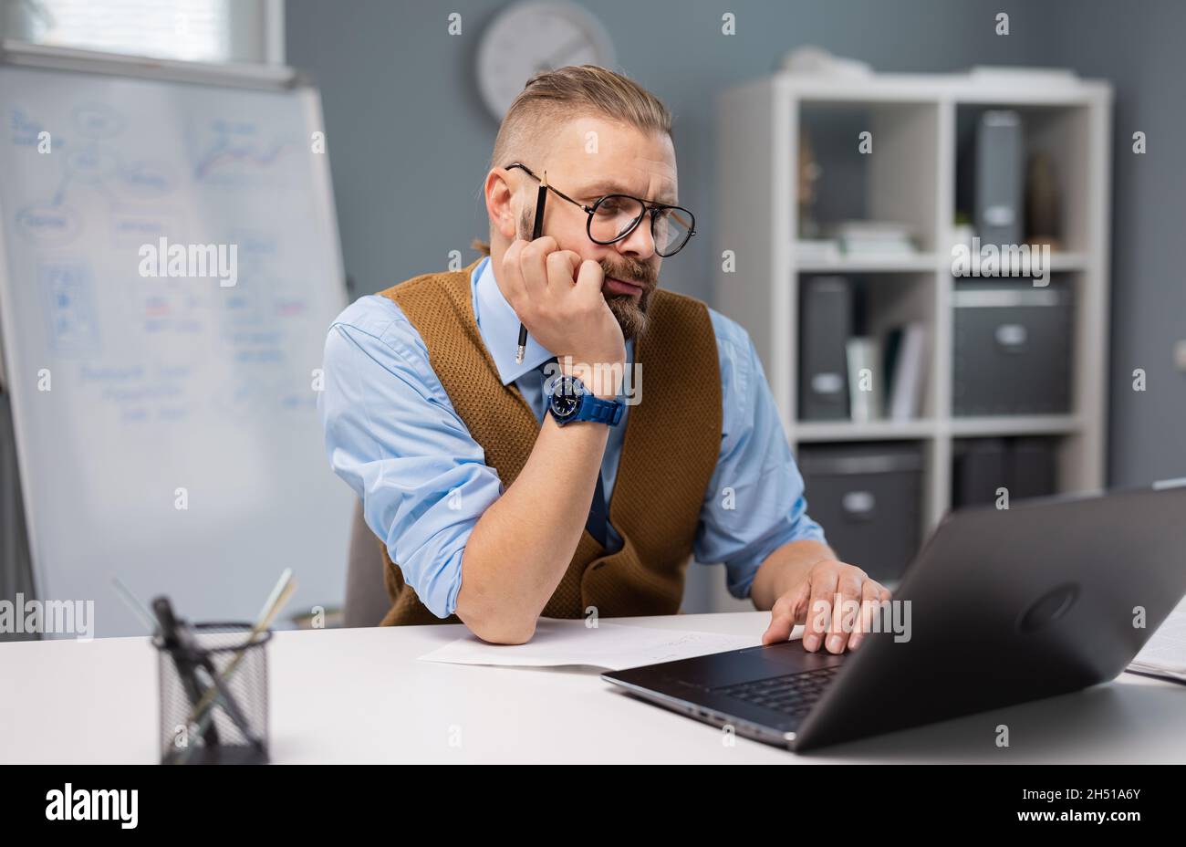 Thoughtful man working on laptop Stock Photo