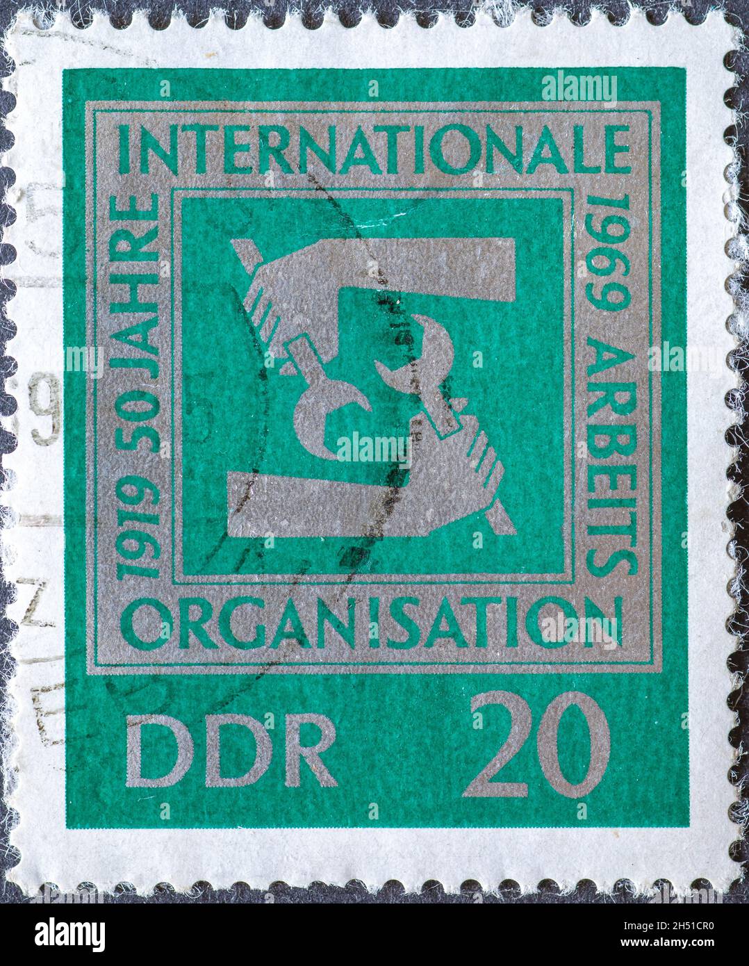 GERMANY, DDR - CIRCA 1969: a postage stamp from Germany, GDR showing hands with wrenches. Text: 50 years of international labor organization Stock Photo