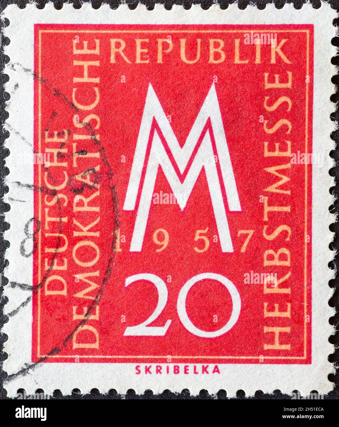 GERMANY, DDR - CIRCA 1957 : a postage stamp from Germany, GDR showing MM the trade fair symbol of the Leipzig Autumn Fair in 1957.  red Stock Photo
