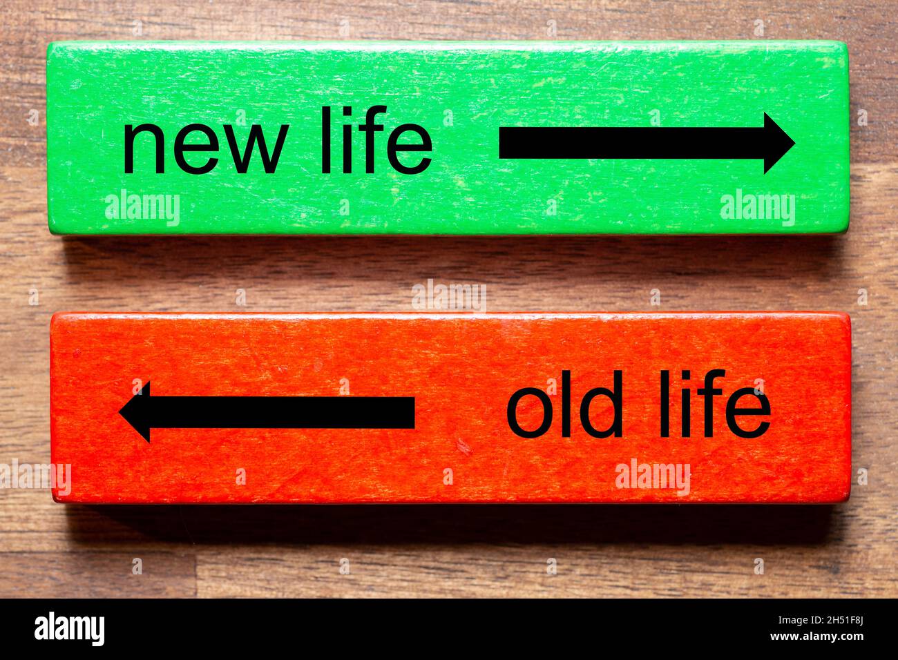 new life is written on a green block and old life is the text on a red block. The background is a dark wood background. Stock Photo