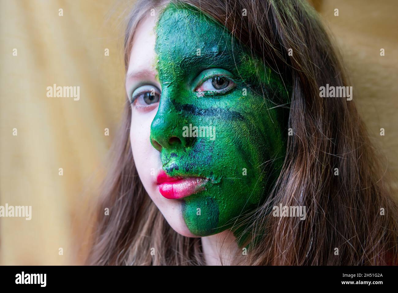 Teenage girl activist with half green make-up or face paint for a climate protest, concept of environmental concern, going green Stock Photo