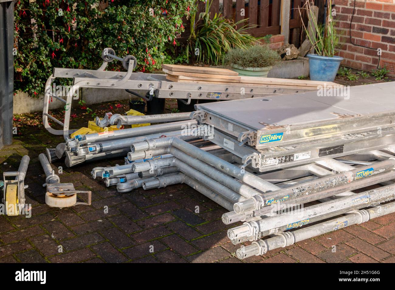 Pile of components of hired scaffolding or mobile platform work tower in domestic garden Stock Photo