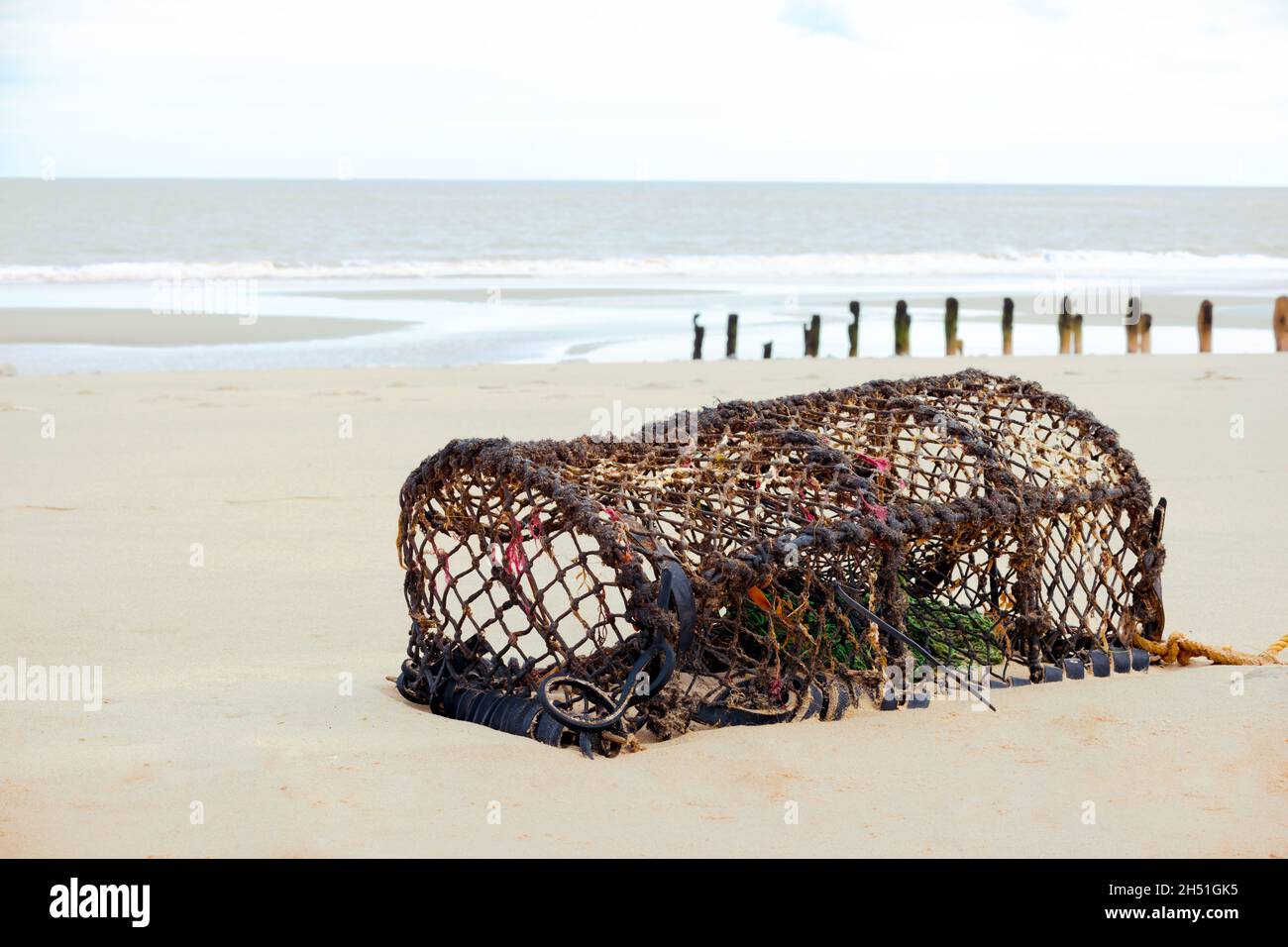 A discarded lobster trap or pot washed ashore onto a beach Stock Photo