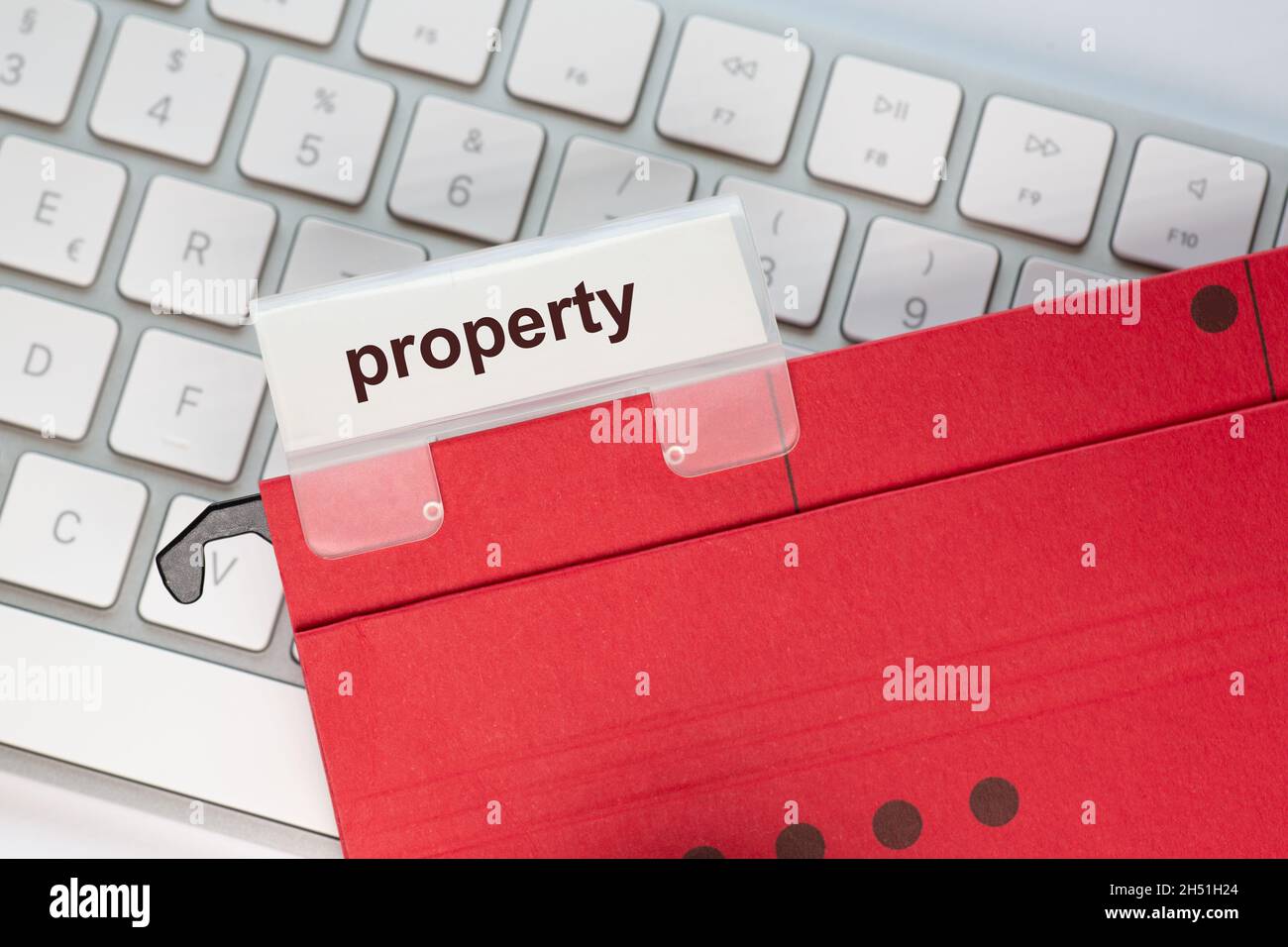 red hanging folder on a keyboard has a tab with the word property on it Stock Photo