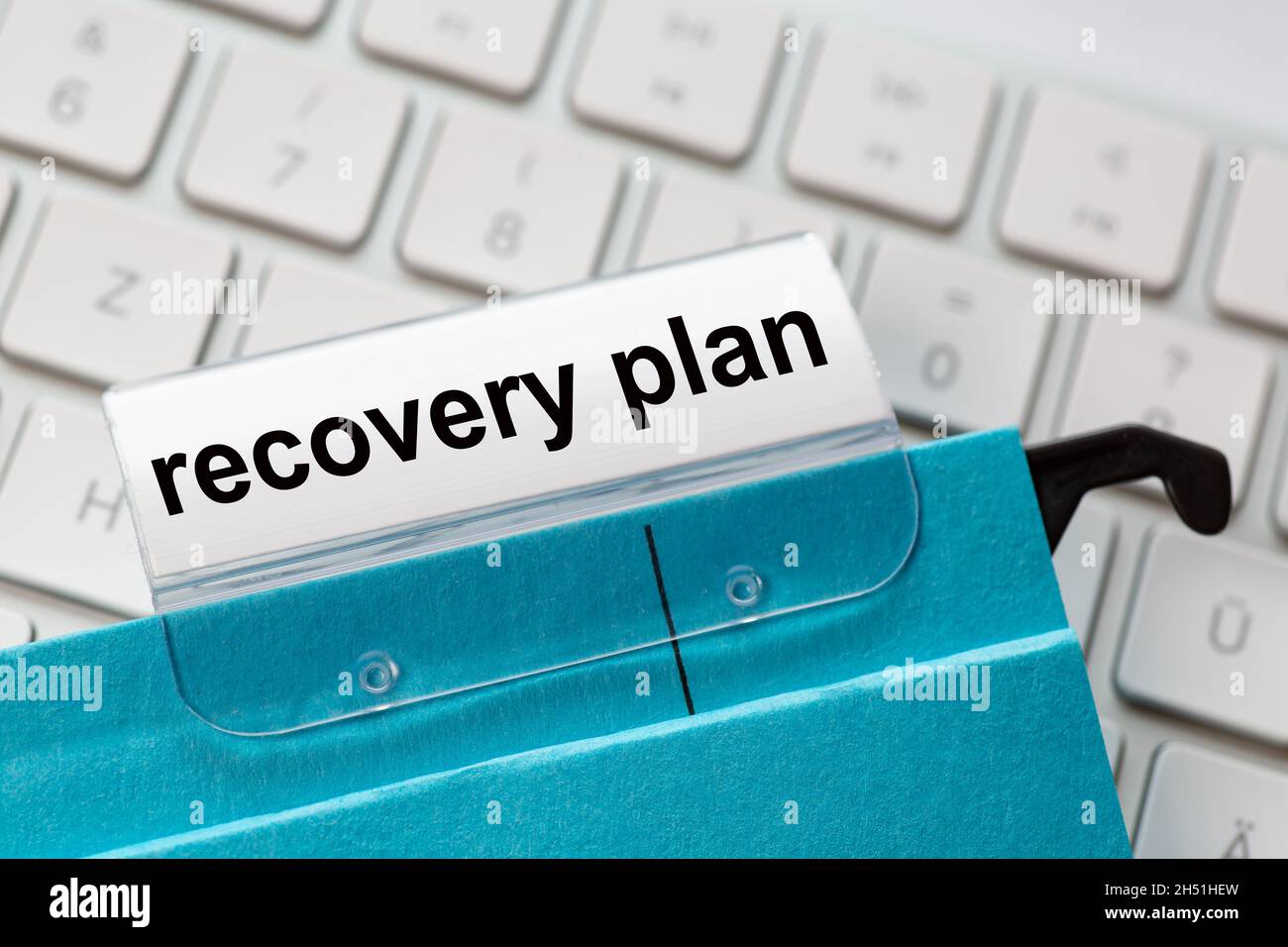 recovery plan is on a label of a blue hanging file. In the background a computer keyboard Stock Photo
