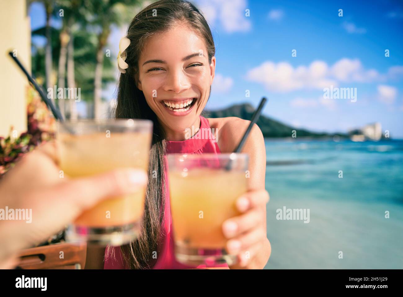 Cocktail toast couple going out on beach restaurant cheering with rum mai tai drinks on Waikiki