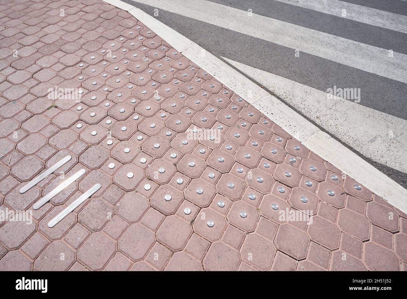 Paving slabs with anti-slip metal inserts for a crosswalk road. Stock Photo
