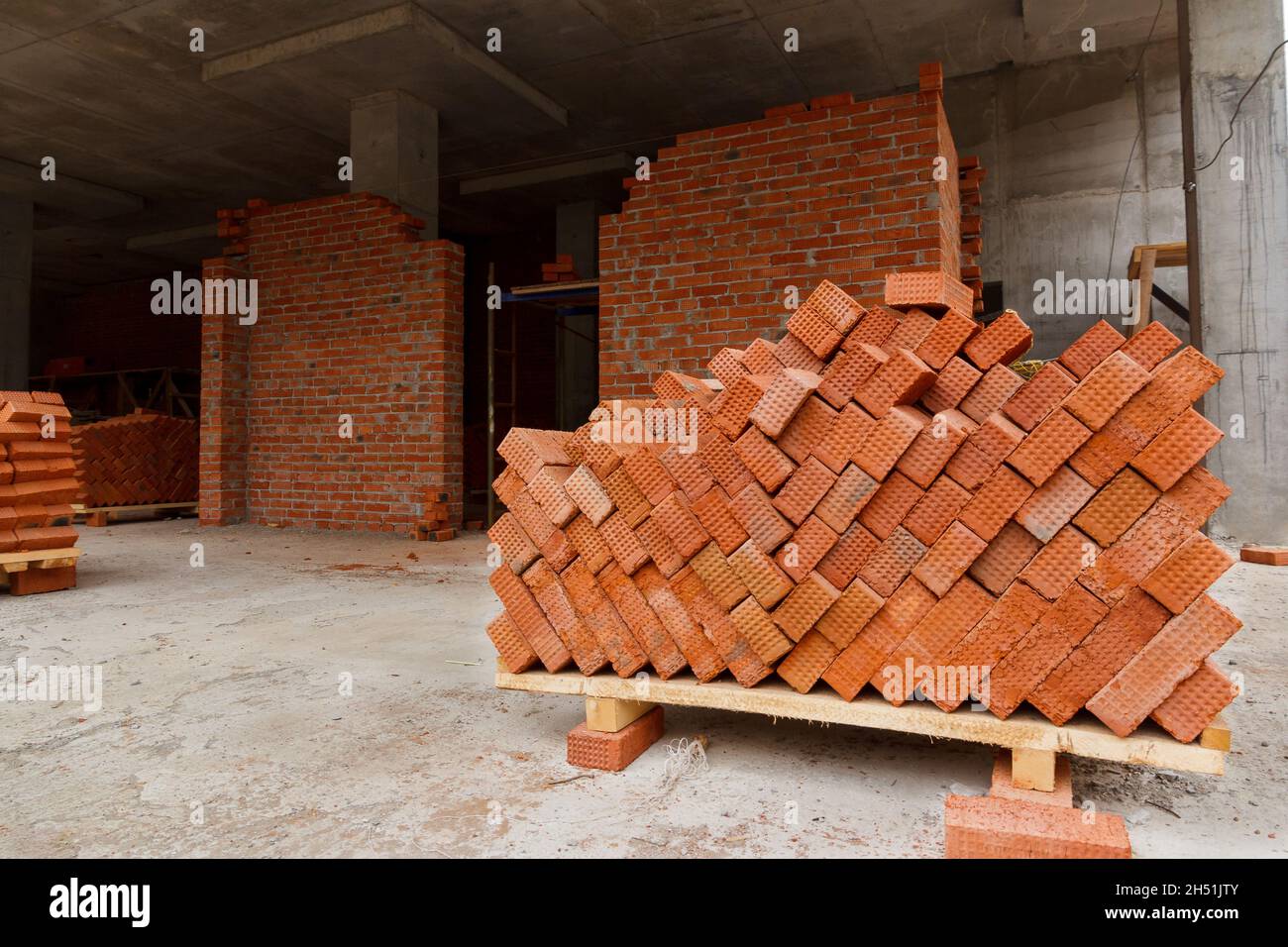 Red building bricks. Brick on a pallet at a construction site. Building material for the construction of walls and partitions in the building. Stock Photo
