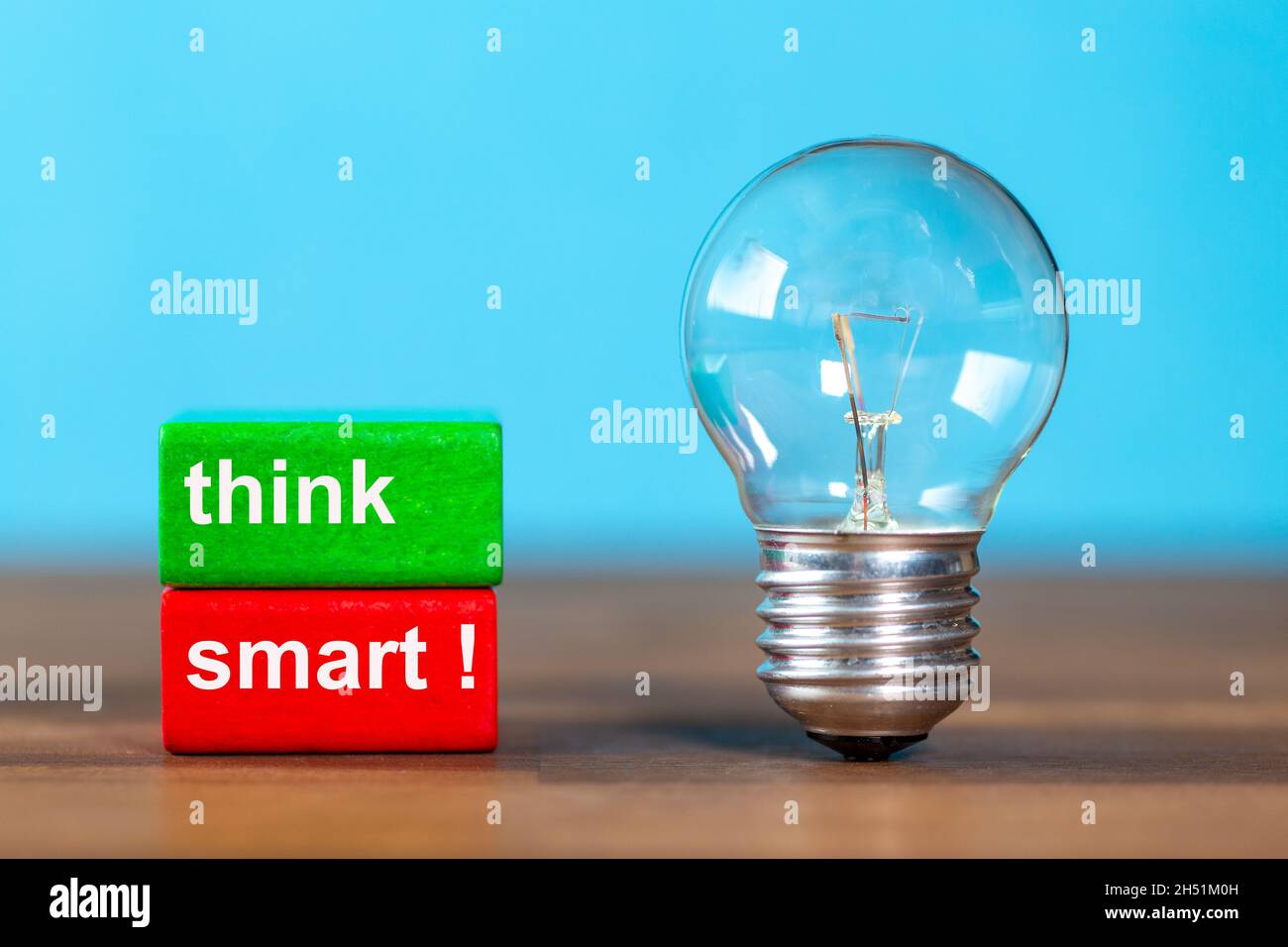 two blocks with the words think smart next to a free-standing antique light bulb against a blue background Stock Photo