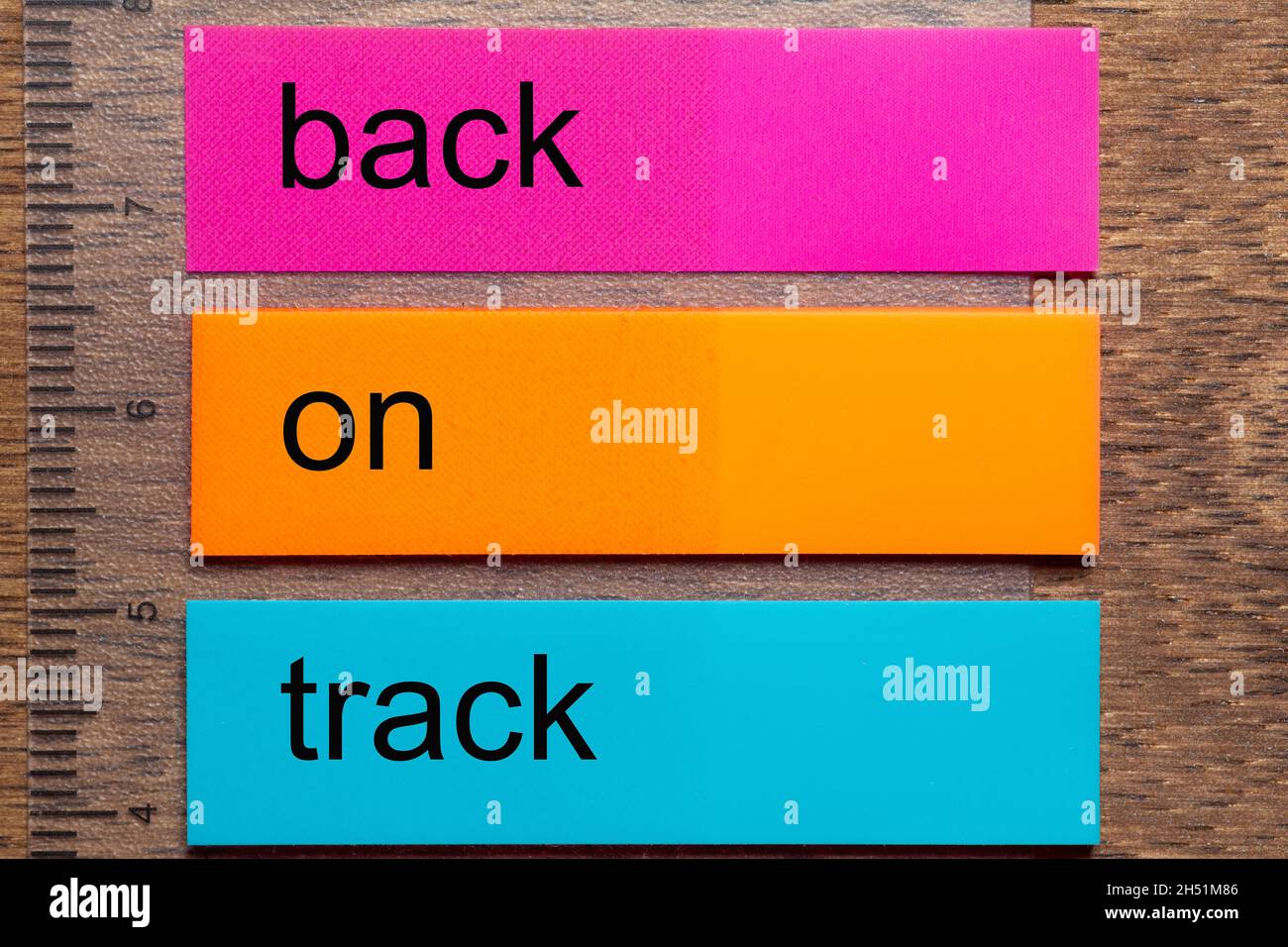 Three bookmark stickers with the words back on track, on a dark natural wooden table Stock Photo