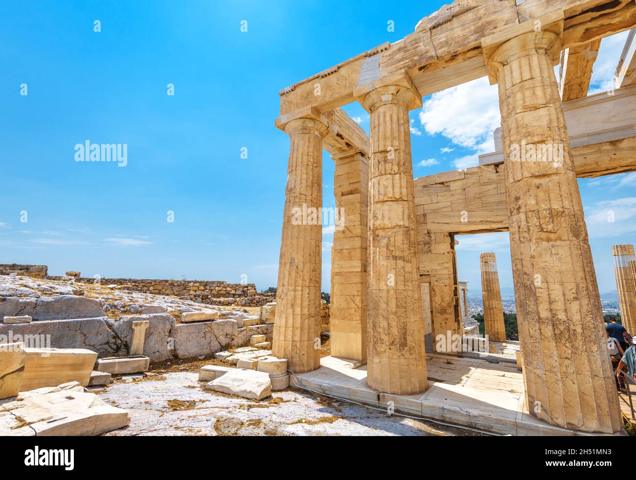 Ancient Greek ruins on Acropolis, Athens, Greece. Remains of Propylaea Palace on blue sky background in Athens city center. Concept of past civilizati Stock Photo