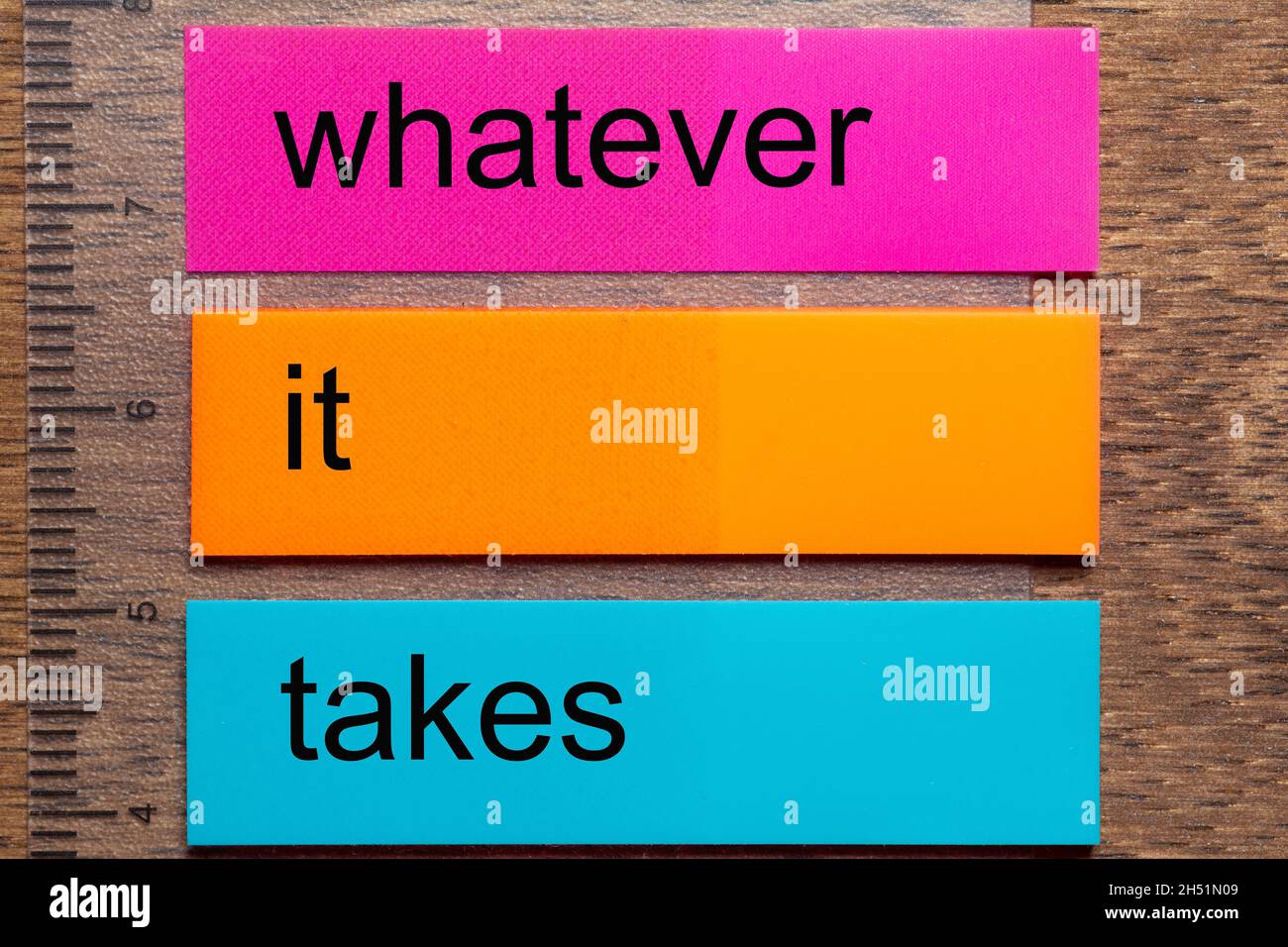 Three bookmark stickers with the words whatever it takes, on a dark natural wooden table Stock Photo