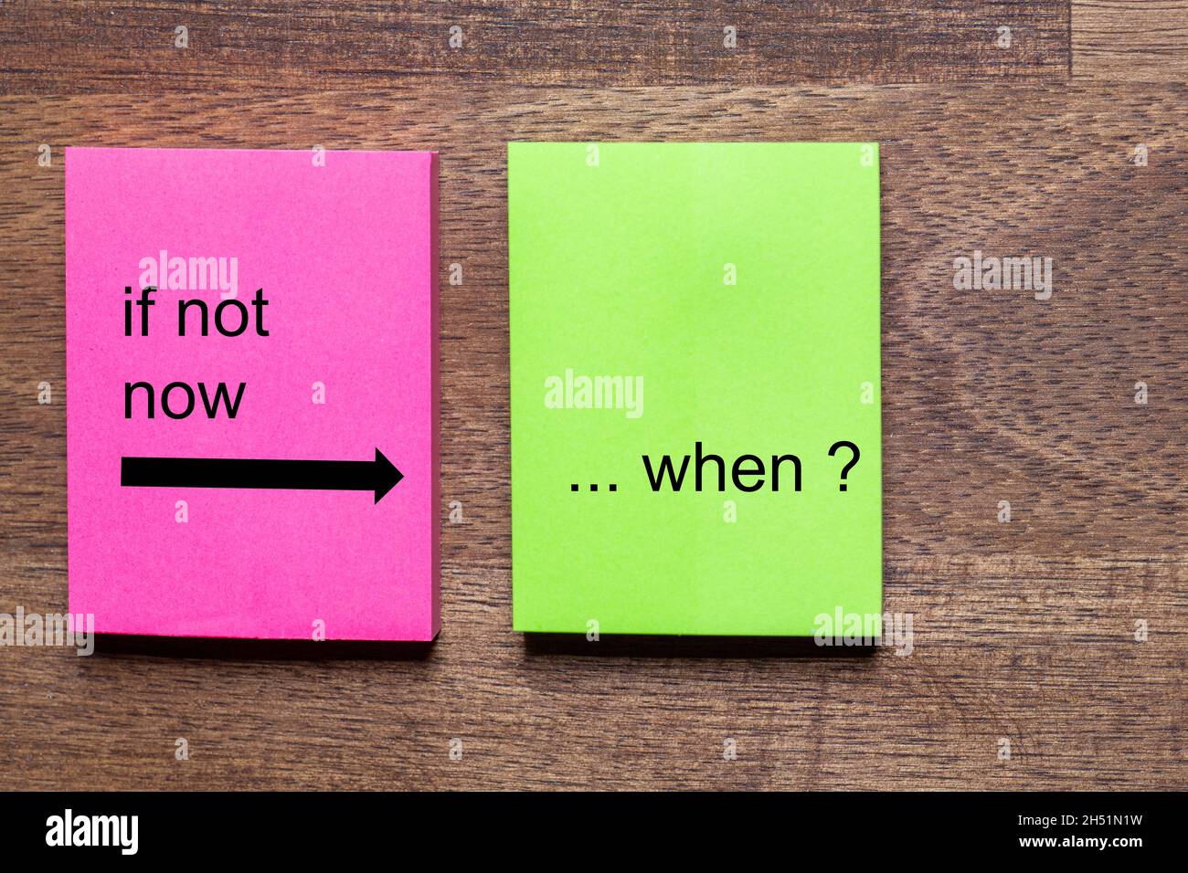pink and yellow note stickers with the motto: if not now, when? Background dark wooden table Stock Photo