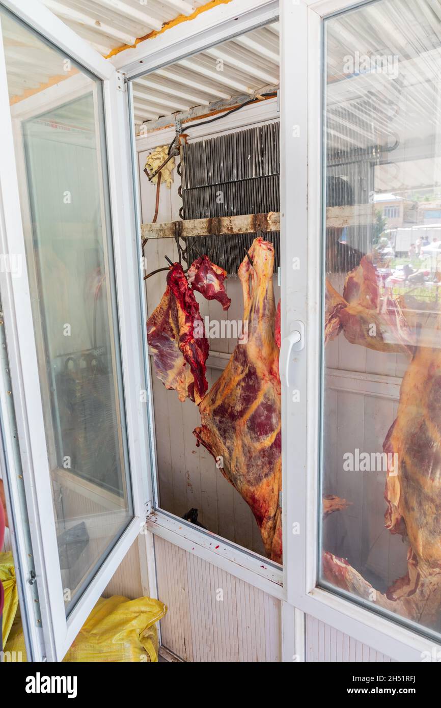 Sarvoda, Sughd Province, Tajikistan. Meat hanging in a cooler in a butcher shop. Stock Photo