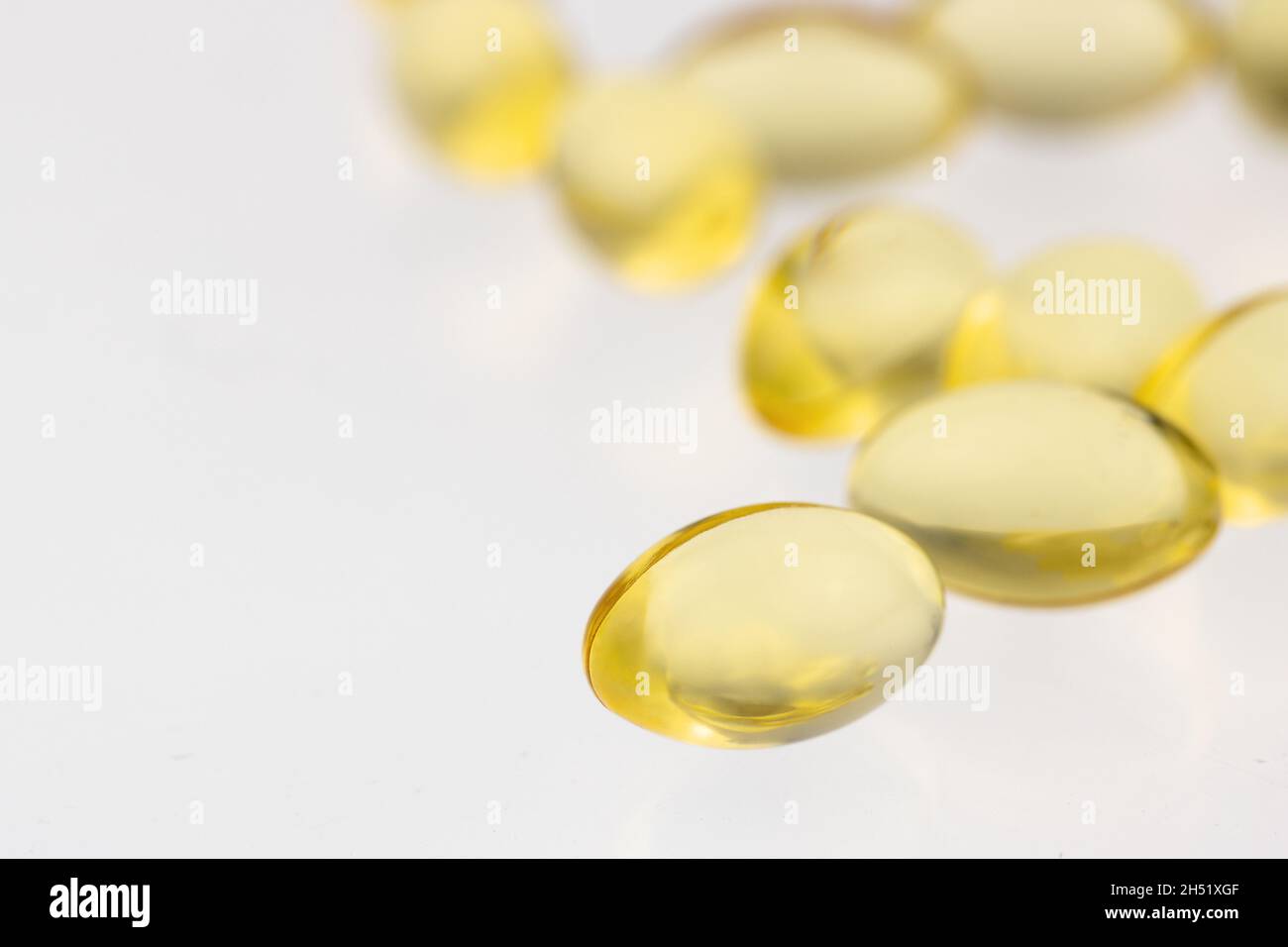 grouping of multiple gel tabs of fish oil, vitamin D or E supplements on a soft white background with shallow depth of field and copy space Stock Photo