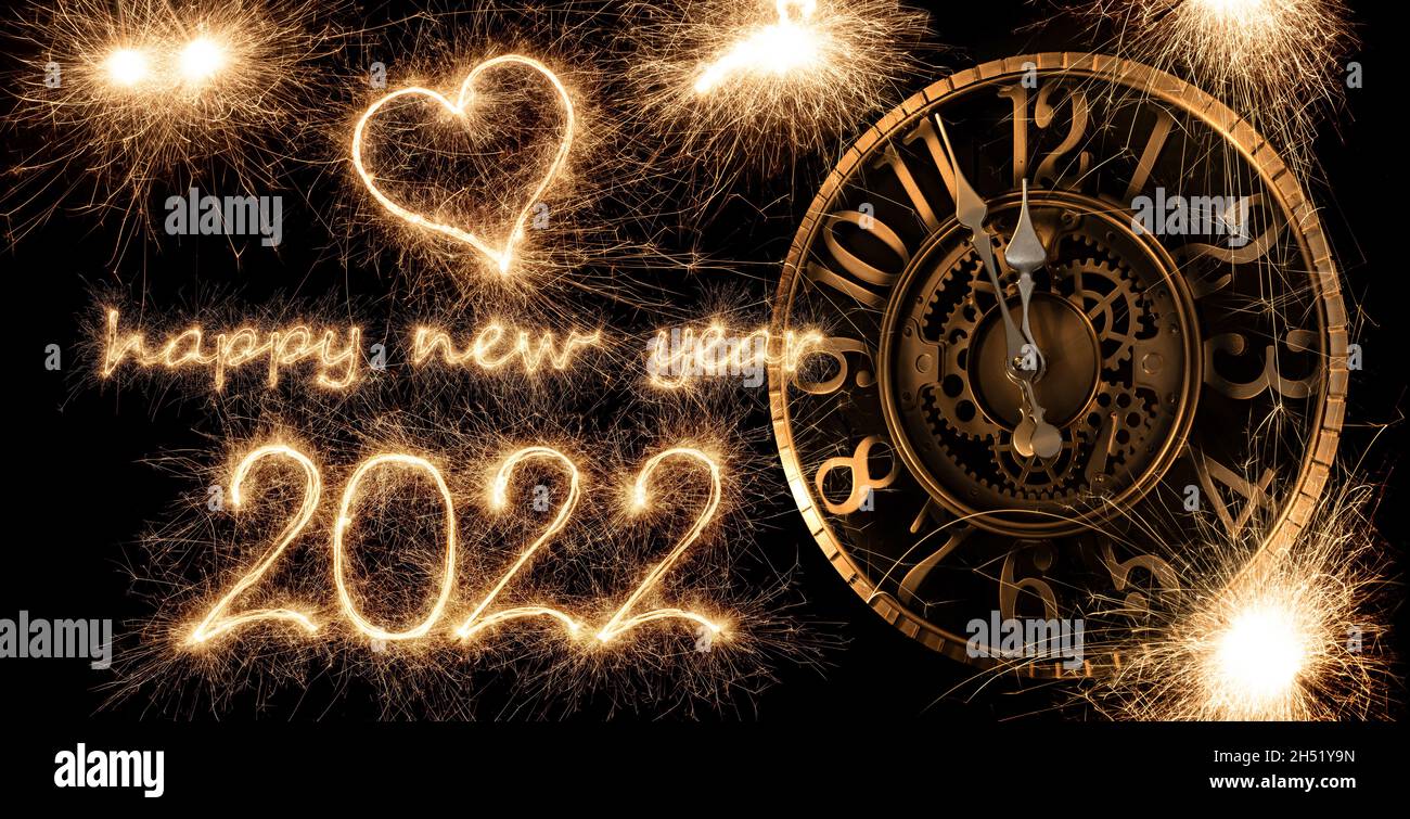 happy new year 2022 greeting with clock ticking. golden bright modern sparkler number and letter isolated on black. silvester eve celebration backgrou Stock Photo