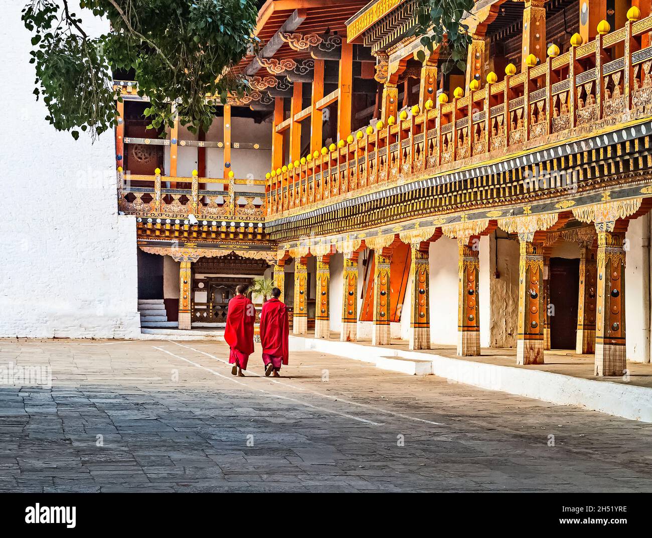 Two Buddhist monks in their traditional red dress walking in the monastery Punakha Dzong courtyard, Bhutan. Stock Photo