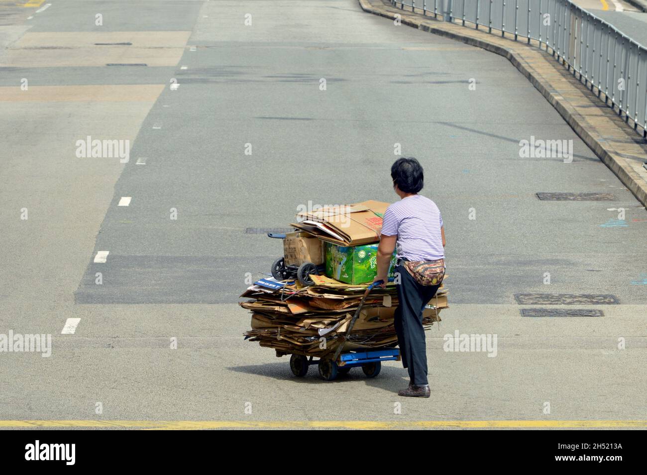 Cardboard collector crossing the road in Hung Hom, Kowloon, Hong Kong Stock Photo