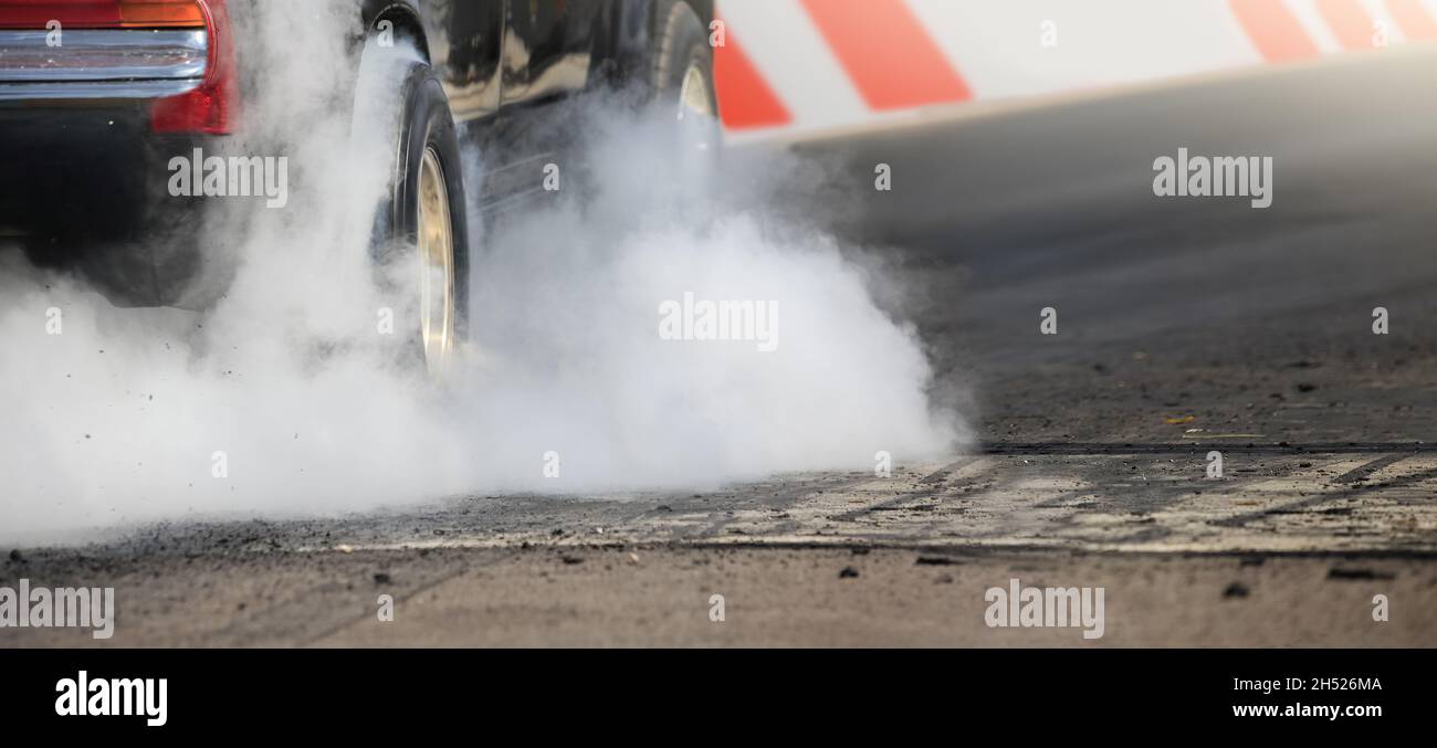 Drag racing car burns rubber off its tires in preparation for the race ...