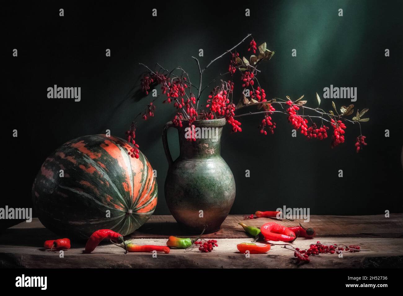 Classic still life with big striped pampkin, beautiful Berberis barberry branch with red berries in ancient vintage jug and hot red paprkia on wooden Stock Photo