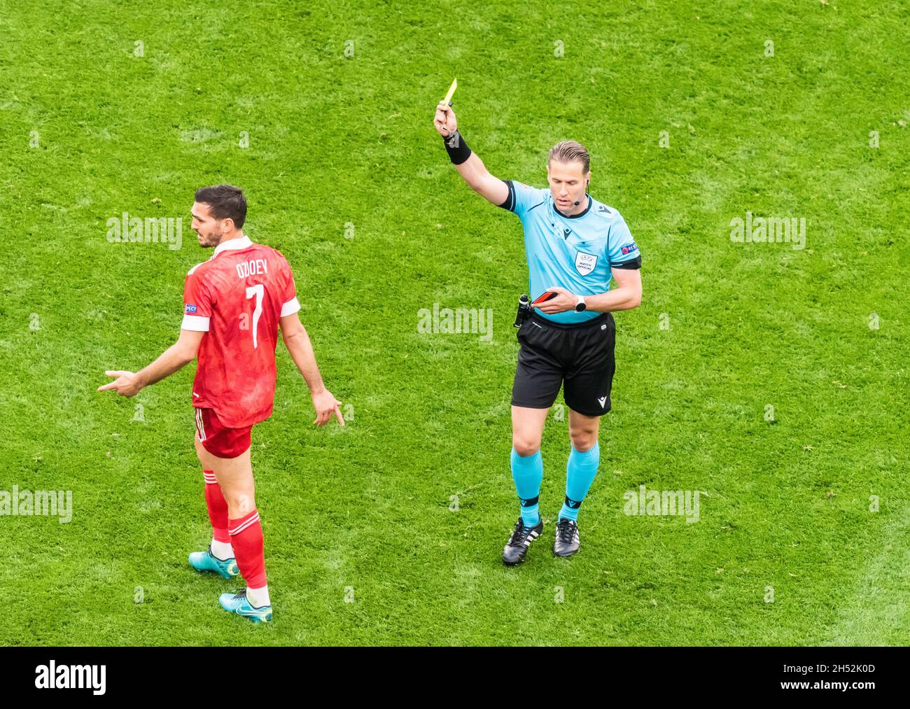 Saint Petersburg, Russia – June 16, 2021. Dutch referee Danny Makkelie showing a yellow card to Russia midfielder Magomed Ozdoyev during EURO 2020 mat Stock Photo