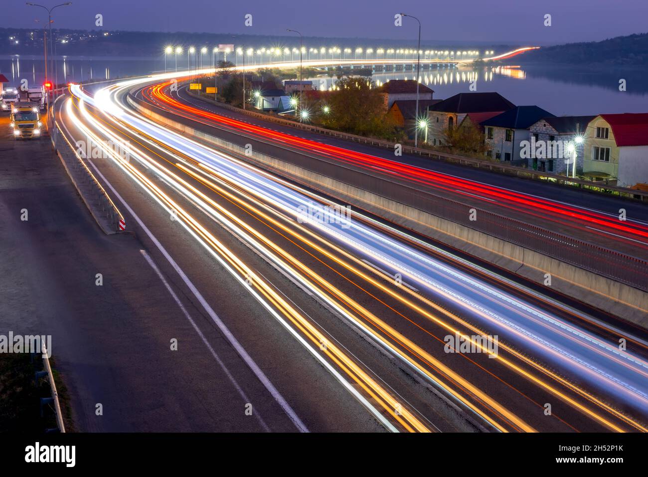 Suburban highway in the late evening. Traces from headlights and taillights of heavy traffic and lights on the bridge Stock Photo